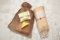 Assortiment artisanal pour le bain et le corps avec serviette turque, ou Peshtemal, jaune, savon au karité et gant exfoliant.