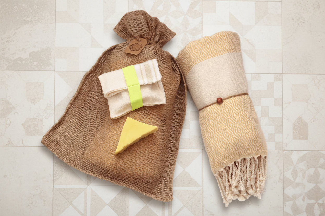 Assortiment artisanal pour le bain et le corps avec serviette turque, ou Peshtemal, jaune, savon au karité et gant exfoliant.