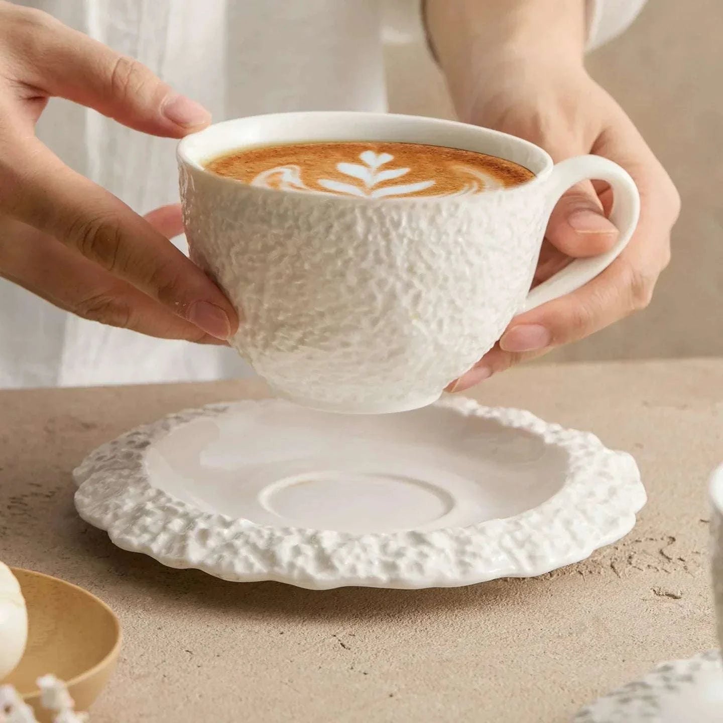 Grande tasse à café et soucoupe minimalistes en céramique texturée.
