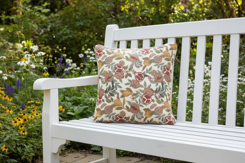 Housse de coussin en tapisserie avec motifs William Morris de grenades et citrons sur banc de jardin.