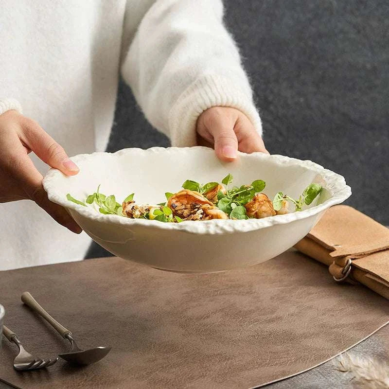 Saladier blanc ivoire artisanal en porcelaine avec bord irrégulier.