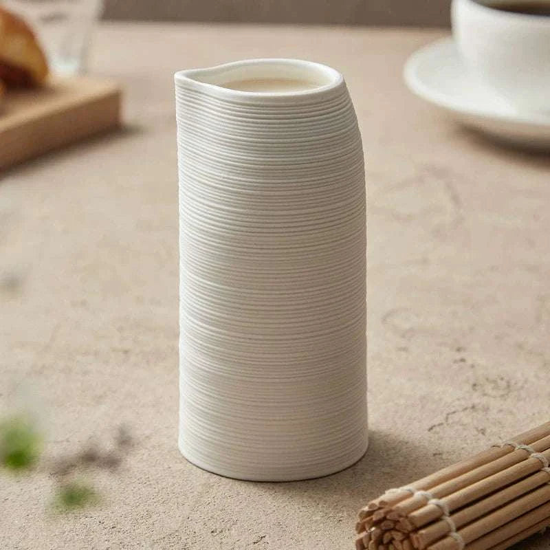 Tasse haute artisanale avec bec verseur, design et minimaliste en céramique striée.