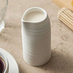 Tasse haute artisanale design et minimaliste en céramique striée avec bec verseur.