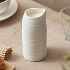 Tasse haute blanche artisanale minimaliste en céramique striée.