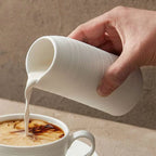 Tasse haute minimaliste en céramique striée artisanale avec bec verseur.