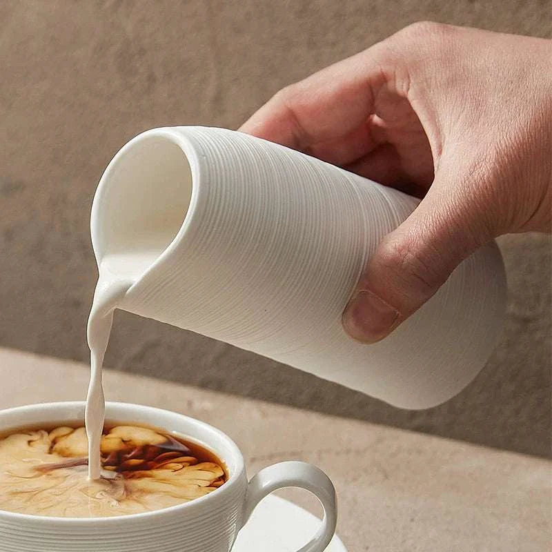 Tasse haute minimaliste en céramique striée artisanale avec bec verseur.