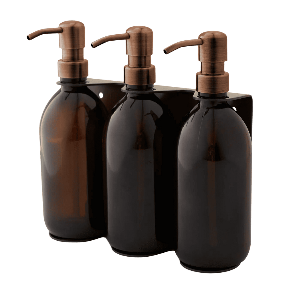 Triple distributeur de savon mural avec flacons verre ambré et pompe cuivrée.
