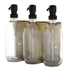 Triple distributeur de savon mural avec flacons verre transparent et pompe noire.