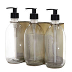 Triple distributeur de savon mural avec flacons verre ambré et pompe plastique noire.